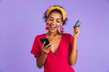 Wall Mural - Happy woman in dress using smartphone while holding credit card