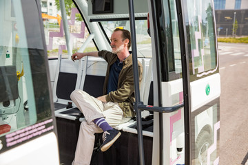 Interior of automated remotely operated bus in Helsinki. Unmanned public transport test on street. Passenger sitting on seat, waiting on bus stop. 