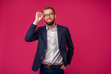 Portrait view of an attractive happy businessman with glasses on a pink background