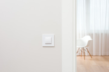 The wall switch is in the bright, contemporary interior. Open the door to the room. The chair by the window