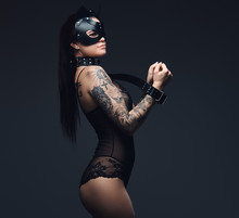 Sexy Woman Wearing Black Lingerie In BDSM Cat Leather Mask And Accessories Posing On Dark Background. 