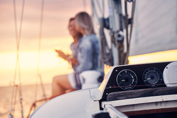 Wall Mural - Female friends relaxing on the yacht with glasses of wine in the hands, during sunset on the high seas.