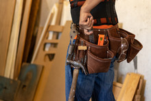 Man With Tool Belt In A Workshop