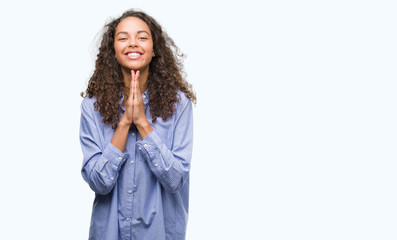 Canvas Print - Young hispanic business woman praying with hands together asking for forgiveness smiling confident.