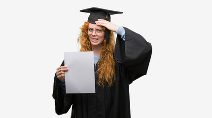 Poster - Young redhead woman wearing graduate uniform holding degree stressed with hand on head, shocked with shame and surprise face, angry and frustrated. Fear and upset for mistake.