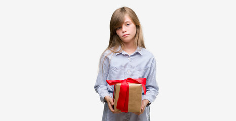 Sticker - Young blonde toddler holding a present with a confident expression on smart face thinking serious