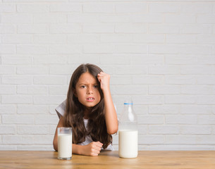 Sticker - Young hispanic kid sitting on the table drinking a glass of milk annoyed and frustrated shouting with anger, crazy and yelling with raised hand, anger concept