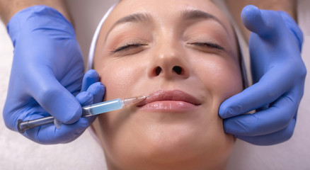 Close up of beautiful woman during lips treatment with hyaluronic acid