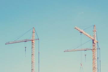 Two yellow cranes on sky background. Toned