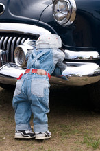 Cute Doll Wearing Jeans Lying On Antique Blue Car