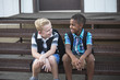 © Brocreative - Candid photo of two students talking together at school. Smiling boys having fun together sitting on the stairs enjoying their friendship