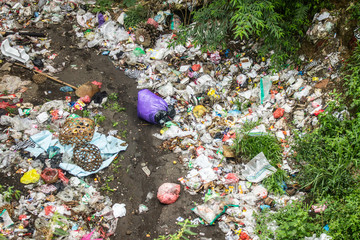 Trash and garbage scattered across drainage area for disgusting pollution photo.