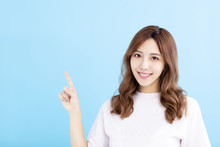Smiling Young Woman Pointing At Blue Background
