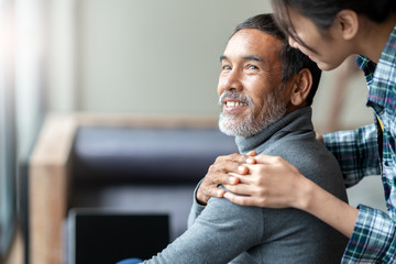 smiling happy older asian father with stylish short beard touching daughter's hand on shoulder looki