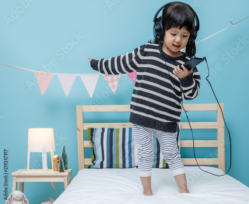 Cute Little Girl Sing A Song With Smartphone In Her Bedroom