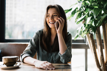 young beautiful woman using mobile phone in modern coffee shop. cute smiling businesswoman holding s