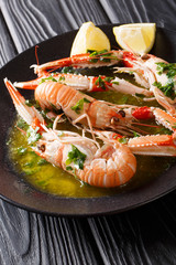 Canvas Print - Delicious boiled scampi or langoustine or Norway lobster close-up on a plate with sauce and lemon on a table. vertical