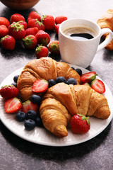 Wall Mural - Delicious breakfast with fresh croissants and ripe berries on old marble background