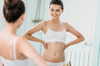 © LIGHTFIELD STUDIOS - beautiful smiling young woman in underwear looking at mirror in bathroom