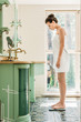 © LIGHTFIELD STUDIOS - side view of beautiful young woman in towel standing on digital scales in bathroom