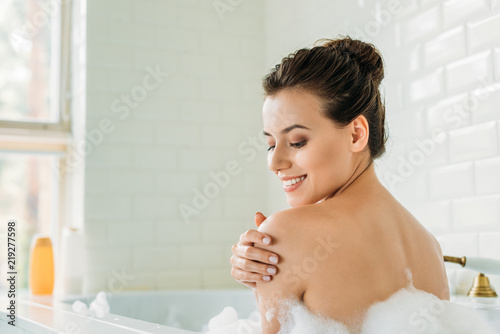 Fotografía beautiful smiling young woman relaxing in bathtub with foam