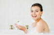 © LIGHTFIELD STUDIOS - beautiful young woman sitting in bathtub with foam and smiling at camera