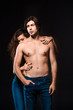 © LIGHTFIELD STUDIOS - partial view of woman hugging shirtless boyfriend in jeans isolated on black