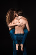 © LIGHTFIELD STUDIOS - back view of shirtless man holding girlfriend in jeans isolated on black
