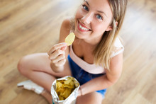 Beautiful Young Woman Eating Patatoes While Sitting On The Floor At Home.