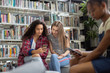 © ReeldealHD images - High school students looking at smartphone in a library
