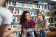 © ReeldealHD images - High school students studying together in a library with a digital tablet