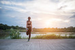 © Johnstocker - Healthy young woman warming up outdoors workout before training session at the park.