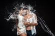 © LIGHTFIELD STUDIOS - portrait of man with black ribbon on eyes hugging sexy girlfriend near by while swilled with water isolated on black