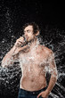 © LIGHTFIELD STUDIOS - portrait of shirtless man drinking water from glass while swilled with water splash isolated on black