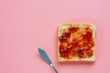 Sliced fine whole wheat bread with strawberry spread on pink background for food and eating concept