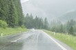 Regennasse Fahrbahn und Regentropfen auf einer Auto Windschutzscheibe