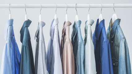 Assorted blue shirts hanging on wooden hangers