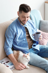 Poster - Young man with cute cat on sofa at home