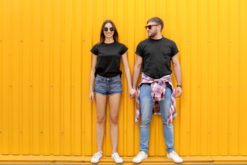 Wall Mural - Young couple wearing black t-shirts near color wall on street