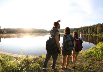 Poster - Young friends on shore of beautiful lake, wide-angle lens effect. Camping season