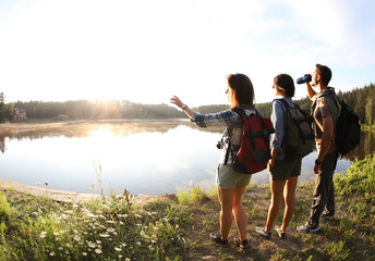 Poster - Young friends on shore of beautiful lake, wide-angle lens effect. Camping season