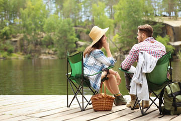 Canvas Print - Young couple resting on pier near lake. Camping season