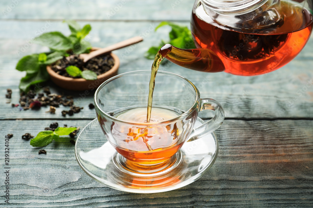 Pouring black tea into glass cup on wooden table Stock Photo | Adobe Stock