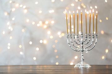 Wall Mural - Hanukkah menorah with candles on table against blurred lights