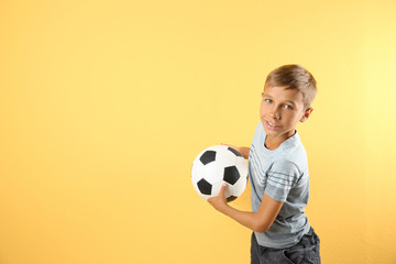 Adorable little boy with soccer ball on color background