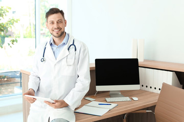 Canvas Print - Male medical assistant near workplace in clinic. Health care service