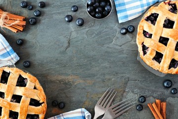 Poster - Rustic homemade blueberry pies with lattice pastry. Top view scene. Frame with copy space over a dark stone background.
