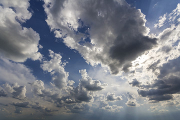 Fantastic panorama view of bright white puffy clouds lit by sun spreading against deep blue summer sky moving with wind. Beauty and power of nature, meteorology and climate changing concept.