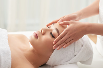 Beautiful Vietnamese woman enjoying sculpting face massage