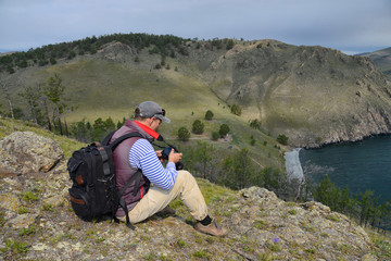 Wall Mural - a man with a camera sitting on a hill